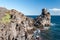 Rocky coastline of lava cliff near Acireale Sicily, with a watchtower in the background