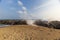 Rocky coastline with long waves lapping with sand and blue sky