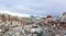 Rocky coastline overcrowded with flock of gentoo penguins and fjord with polar hut in the background, Peterman island, Antarctic