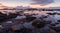 A rocky coastline with tide pools, catching the last light of the day