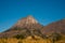 The rocky and conical shaped mountain rises steeply from the grassy plains