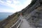 Rocky country near the sea. On the slope of one of the cliffs there is a dirt road along which tourists go