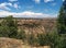 Rocky desert valley with greenery and clouds in sky