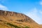 Rocky dry yellow cliff slope against light blue sky