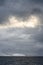 Rocky frozen landscape with stormy gray skies with some clouds highlighted white by the sun, Southern Ocean, Antarctica