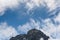 Rocky gray mountain peak with blue sky and wispy white clouds as a nature background