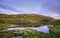 Rocky hill reflecting in a Small Lake at Sunset with Blue Sky and Overcast Clouds (Faroe islands)