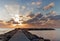 Rocky jetty / pier at sunrise with dramatic cloudy sky and smooth sea, cala bona, mallorca, spain