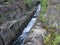 A rocky landscape with trees and rocks in the foreground. Suna River, Poor Porog Waterfall, Girvas