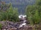 A rocky landscape with trees and rocks in the foreground. Suna River, Poor Porog Waterfall, Girvas