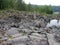 A rocky landscape with trees and rocks in the foreground. Suna River, Poor Porog Waterfall, Girvas