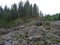 A rocky landscape with trees and rocks in the foreground. Waterfall Poor Porog, Girvas