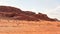 Rocky massifs on red sand desert, bright cloudy sky in background - typical scenery in Wadi Rum, Jordan