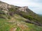 Rocky Mountain, sloping mountain ridge at spring. The forest covers the hills and hiking trail with people. Crimean mountains