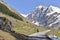 Rocky mountain still snowed in spring at the end of a road where walks the silhouette of a hiker