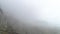 Rocky mountainside in fog. Shot. Top view of rock falls on mountainside. Dense fog envelops rock in autumn cloudy day