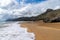 Rocky ocean coast with mountains and a beautiful golden sand beach in the foreground