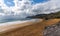 Rocky ocean coast with mountains and a beautiful golden sand beach in the foreground