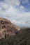 Rocky outcrop and desert plain with cloudy sky.