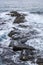 Rocky path in the sea with foamy waves. Beautiful landscape. Vertical