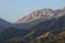 Rocky peaks above the green slopes of the mountains of the Trans-Ili Alatau, illuminated by the morning summer sun.