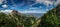 Rocky peaks and old pine trees cover the mountains under a bright blue sky with whispy clouds in Huangshan China