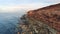 Rocky reef of shore. Shot. Top view of coastline of rocky seashore cliffs of red with holes and sticking stones