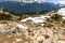 Rocky rocks, boulders, mountain slopes covered with snow, coniferous forests, country roads, blue lake