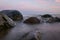 Rocky sea shore before sunrise, dark stone silhouettes and colorful sky