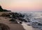 Rocky sea shore before sunrise, dark stone silhouettes and colorful sky