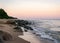 Rocky sea shore before sunrise, dark stone silhouettes and colorful sky