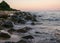 Rocky sea shore before sunrise, dark stone silhouettes and colorful sky
