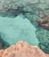 Rocky seabed with blue water and white sand. Mediterranean Sea coast. Lagre stones in the water, vertical top view.