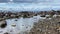 Rocky seashore with a city in the distance. Beautiful sea with small waves.