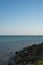 Rocky seashore, clear sky without clouds, two tugboats on the horizon.