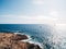 Rocky seashore. Sailboats sail in the distance under the bright sun