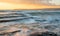 Rocky seashore seascape with wavy ocean during sunset