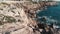 Rocky seashore with stormy strong waves hitting cliffs and splashing. Aerial drone shot of coral rocky beach with waves colliding