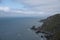 Rocky seawall hill side with ocean body of water and cloudy sky to the left