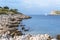 The rocky shore of the island of Lavsa, Croatia, and the yacht going to the sea