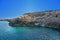 Rocky shore with large stones, turquoise and blue clear water. Transparent clear blue sky