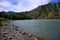 The rocky shore of a mountain turquoise river at a bend at the foot of high mountains