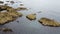 Rocky shore, top view. Big rocks in the water. Seascape. Brown rock formation on body of water