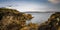 Rocky shoreline with turquoise pools and the historic Broadhaven Lighthouse on a clifftop promontory