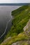 Rocky steep forested and grassy shore of the river bay in cloudy weather. Panoramic view of the river in summer in cloudy weather