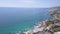 Rocky Victoria beach, drone aerial view descending above colorful coastal urban houses rooftops, Laguna