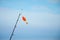 A rod with float bobber at the top in natural setting with sea on background.