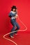 Rodeo. Portrait of beautiful young woman in jeans clothes and black hat posing with string like cowboy against red