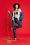 Rodeo. Portrait of beautiful young woman in jeans clothes and black hat posing with string like cowboy against red