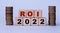 ROI 2022 - acronym on wooden cubes on a light background with coins